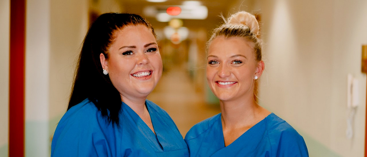 Pflegefachpersonen in typischer Dienstkleidung lachen