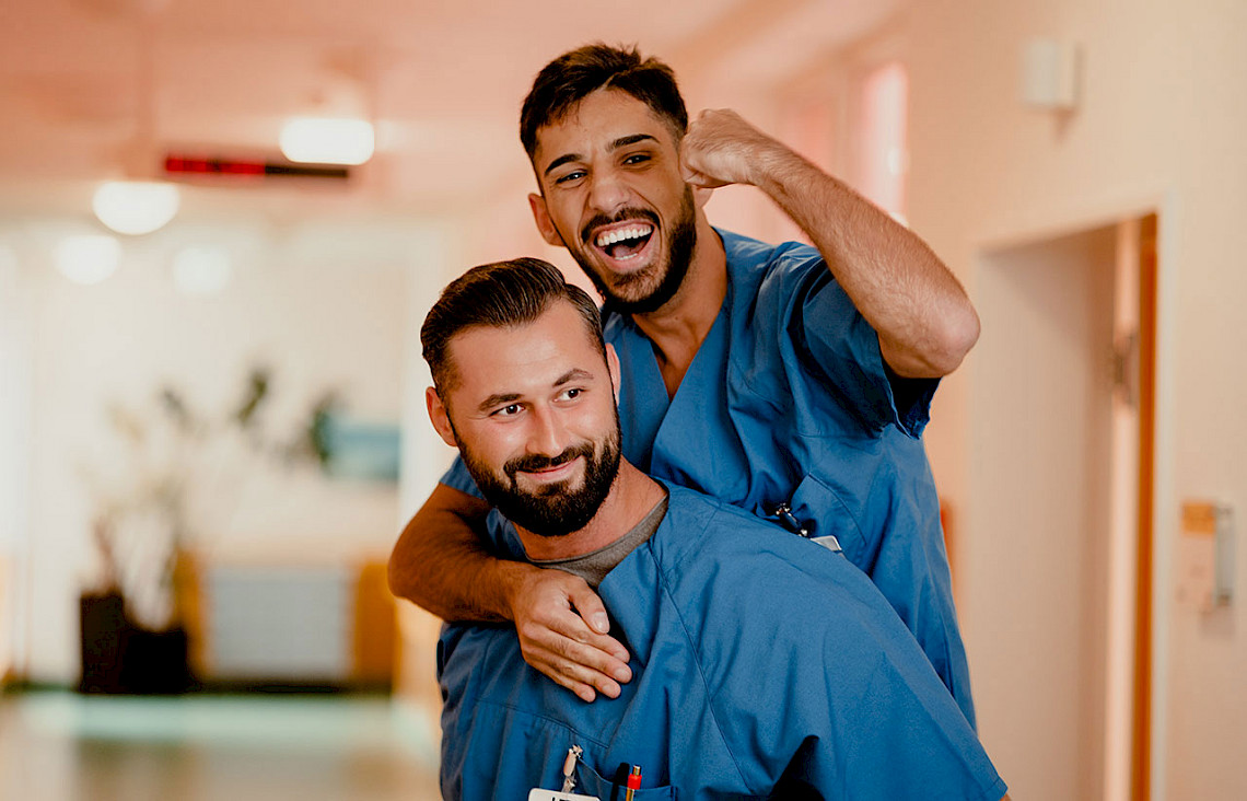 Pflegepersonen lachen und machen eine Siegerpose