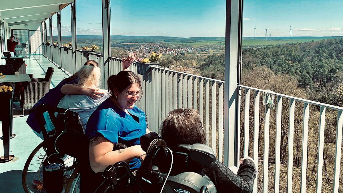 Patienten und Pflegepersonal sitzen auf der Terrasse und genießen den Ausblick