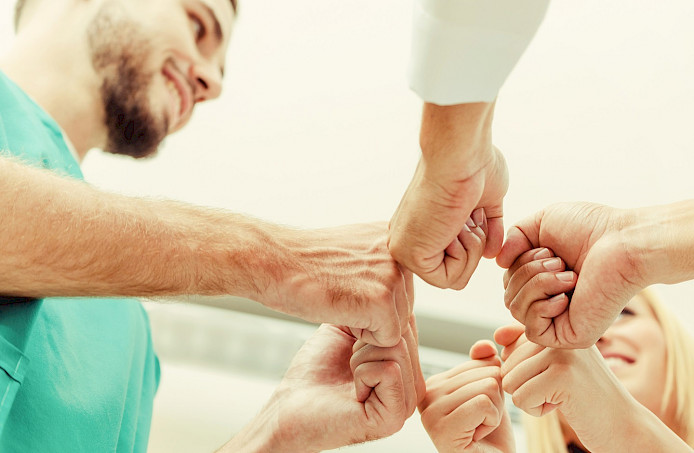 Bild zeigt ein Team. das Zusammenhalt symbolisiert